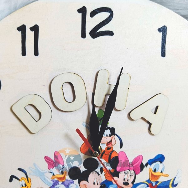 alt="Enfant heureux pointant son prénom sur l'horloge murale colorée dans sa chambre"